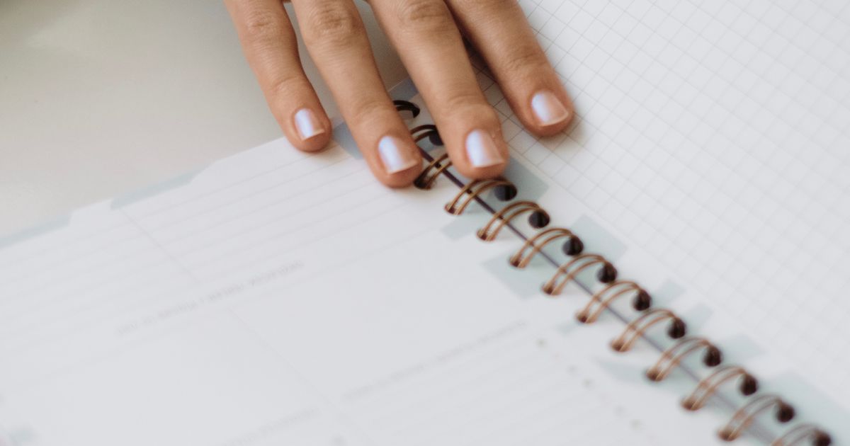 A hand resting on an open planner ready for notes