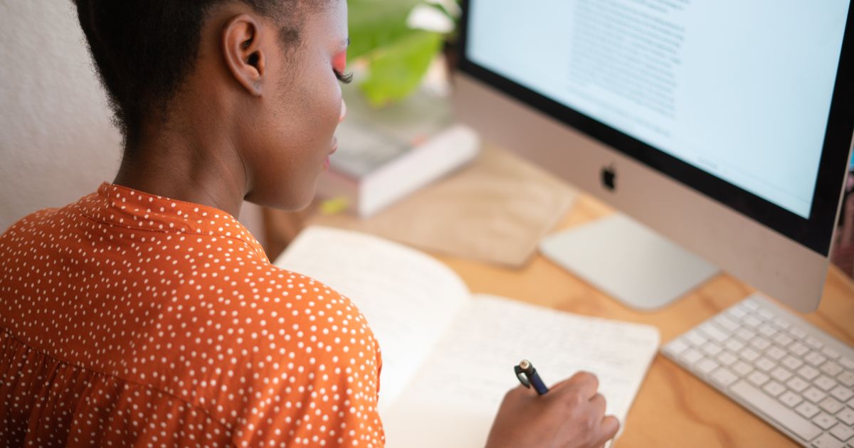 A person planning ideas in a notebook beside a computer
