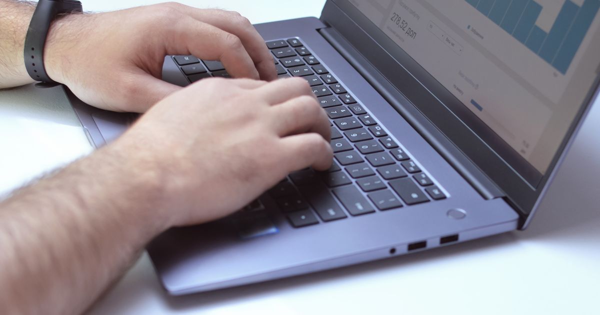 Hands using a laptop displaying analytical charts
