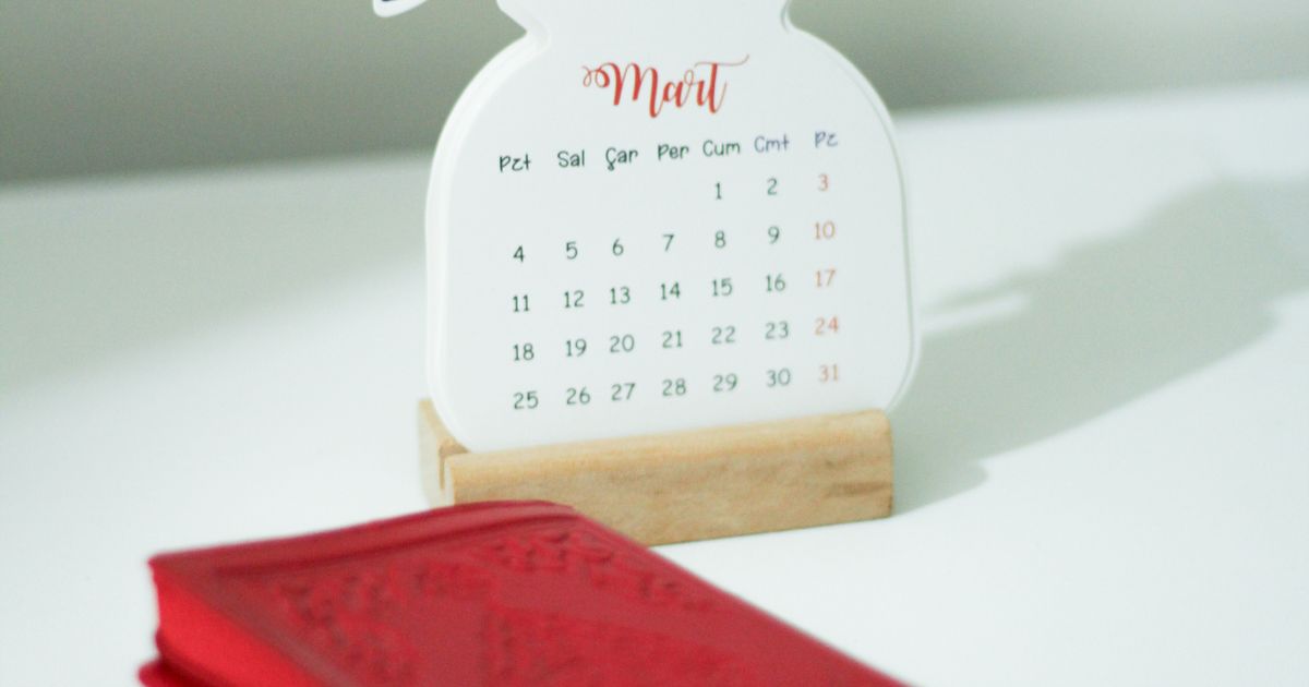 A paper calendar and notebook arranged on a light desk